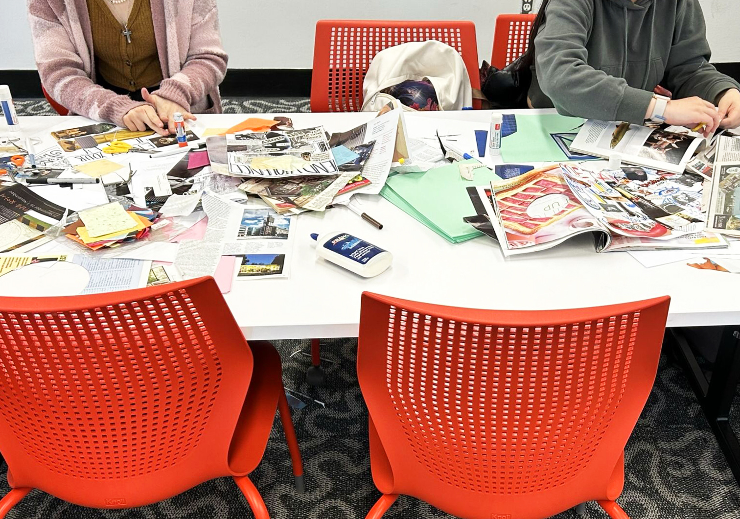 Two students are cutting images out of magazines to make a collage.