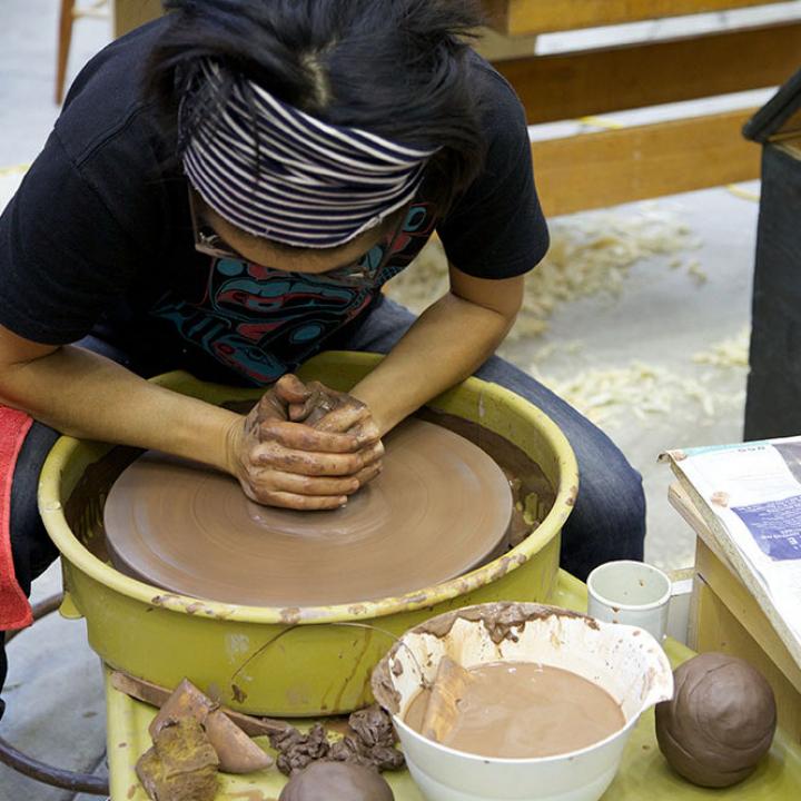 A woman bends over a pottery wheel