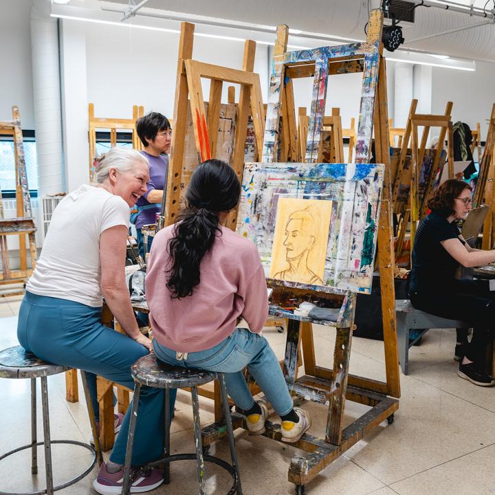 Teacher working with a student painting on a easel