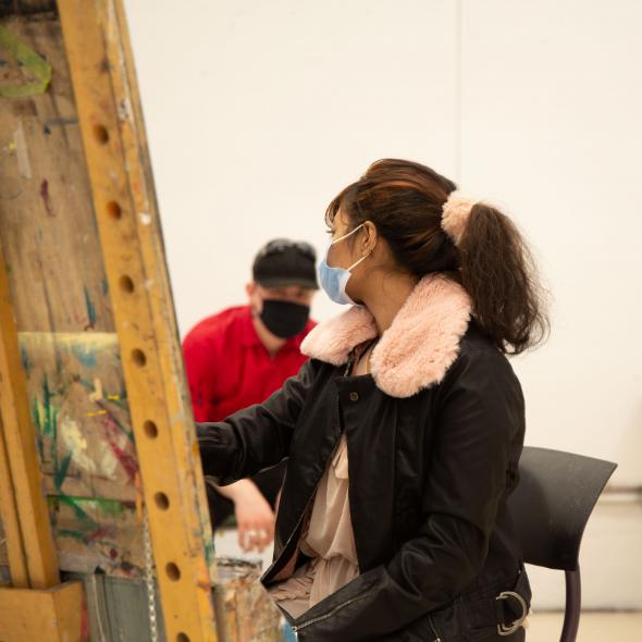 Girl looking over shoulder while painting. 