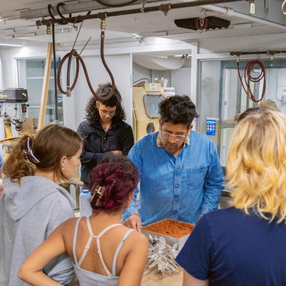 Residency participants crowded around professor as he goes through a demo in the mold-making studio