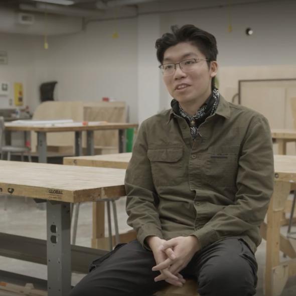 EAD program alum is seated in an OCAD U studio space and faces the camera.